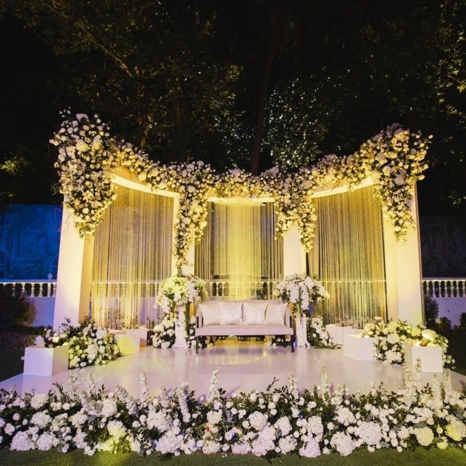 Elegant white floral wedding stage with warm lighting